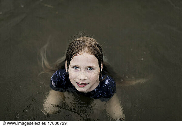 Girl with brown hair swimming in lake water