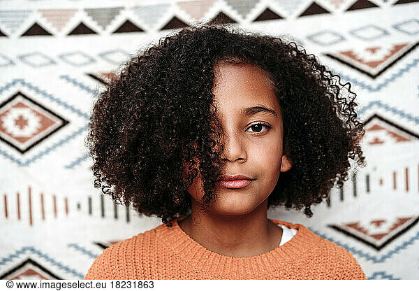 Girl with curly hair in front of patterned backdrop