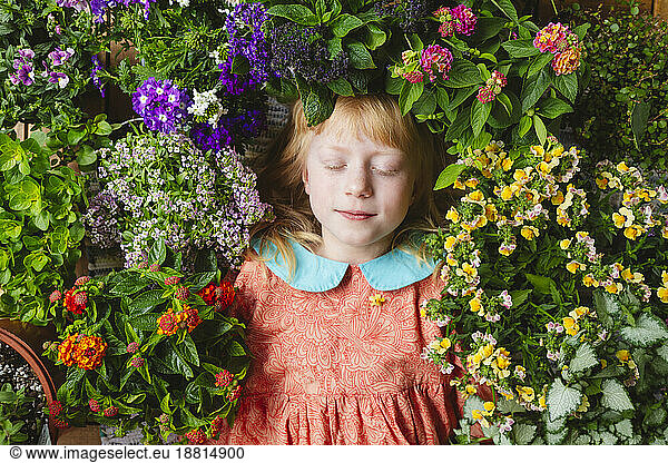 Girl with eyes closed lying amidst flowers