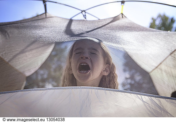 Girl with eyes closed shouting in tent