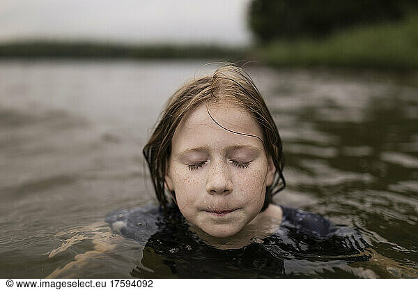Girl with eyes closed swimming in lake