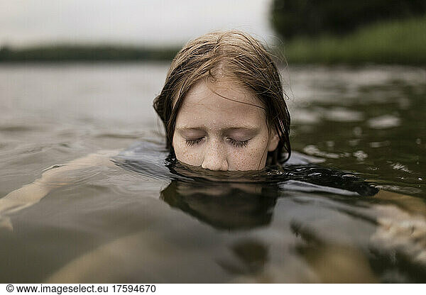 Girl with eyes closed swimming in lake