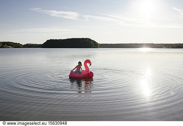 Girl with flamingo pool float on a lake