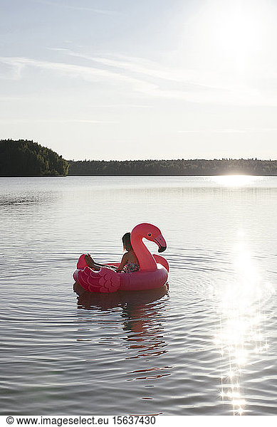 Girl with flamingo pool float on a lake