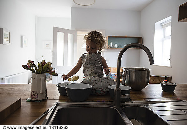 Girl with food sitting on kitchen counter
