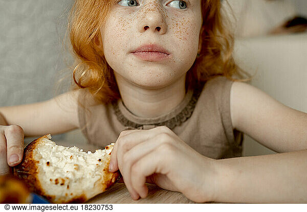 Girl with freckles on face eating cheesecake at home