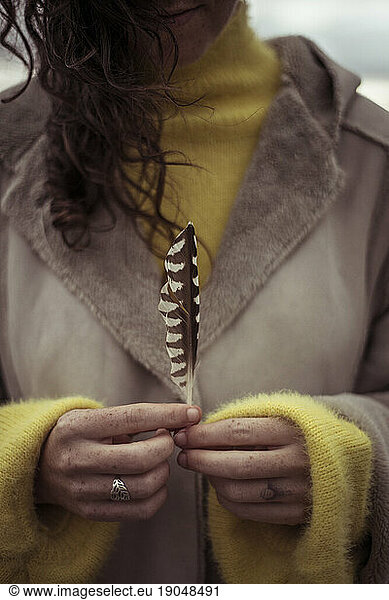 Girl with freckles on hands holds feather