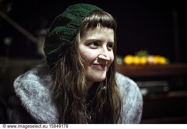 girl with fringe and beanie smiles and listens at night to friends