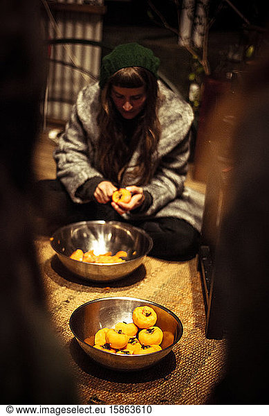girl with fringe in beanie cuts fresh fruit to prepare meal on farm