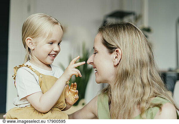 Girl with gold glitter on hands touching mother's nose