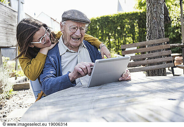 Girl with grandfather using tablet PC at table