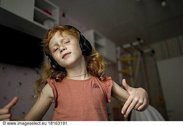 Girl with headphones listening to music and gesturing at home