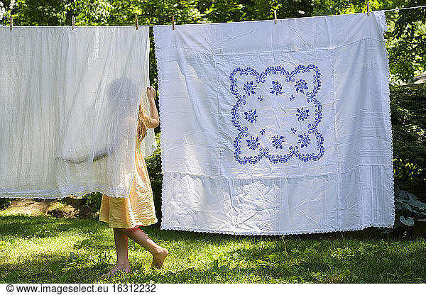 Girl (6-7) with laundry in backyard