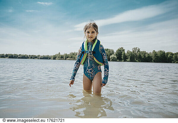 Girl with lifeguard jacket standing in lake