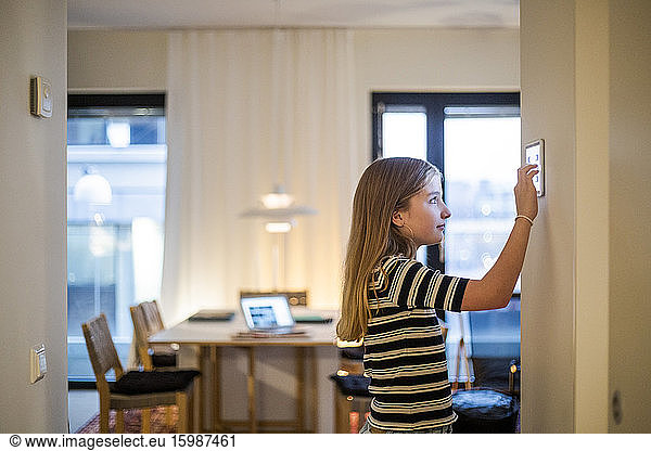 Girl with long hair using digital tablet mounted on wall at home