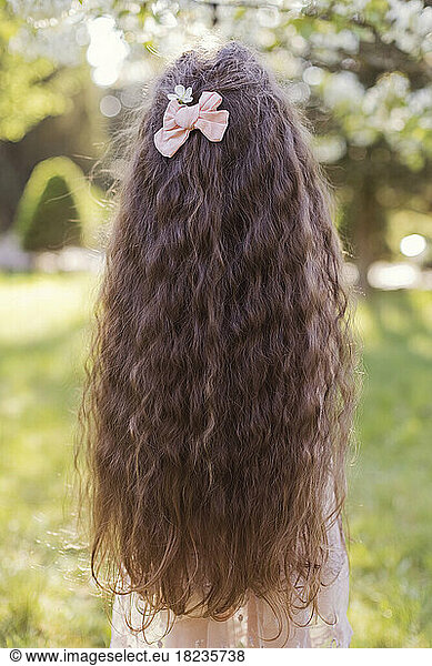 Girl with long wavy hair wearing pink bow