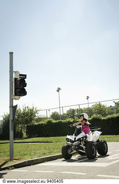 Girl with quadbike waiting at traffic light on driver training area