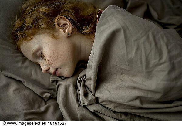 Girl with red hair sleeping in bed at home