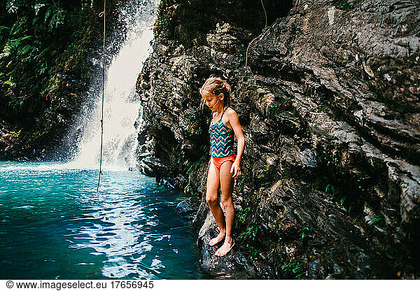 Girl with rope swing in tropical pool with waterfall