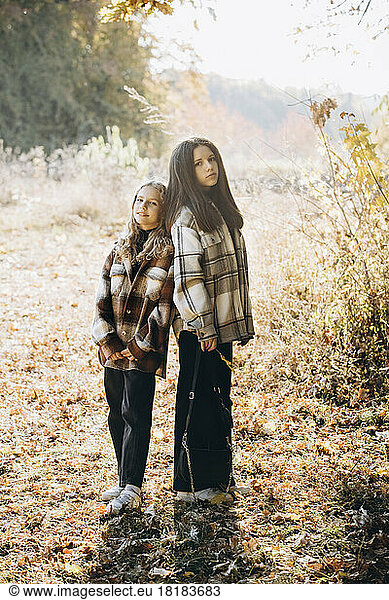 Girl with sister standing in autumn forest