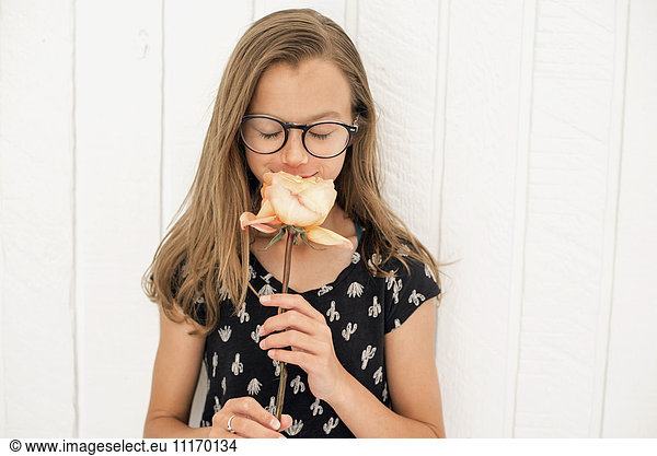 Girl with spectacles smelling a rose.