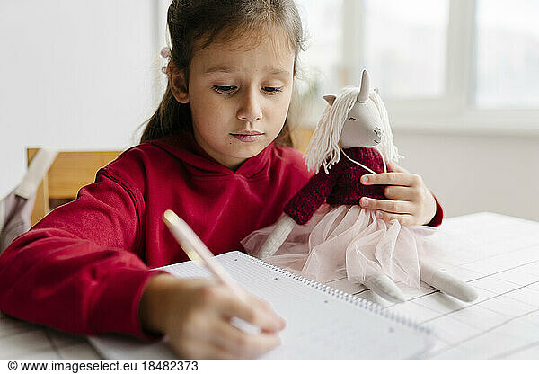 Girl with unicorn toy studying at home