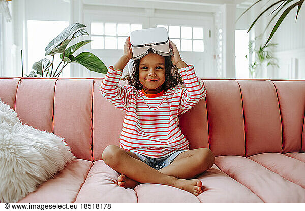 Girl with virtual reality simulator sitting on sofa at home
