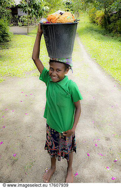 Girl with washing on her head on Fergusson Island  D'Entrecasteaux Islands  Papua New Guinea; Fergusson Island  Milne Bay Province  Papua New Guinea