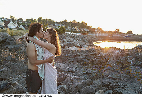 Girlfriend and boyfriend kissing while standing on rock