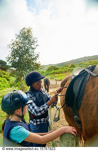Girls adjusting stirrups for horseback riding