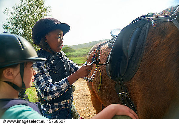 Girls adjusting stirrups for horseback riding