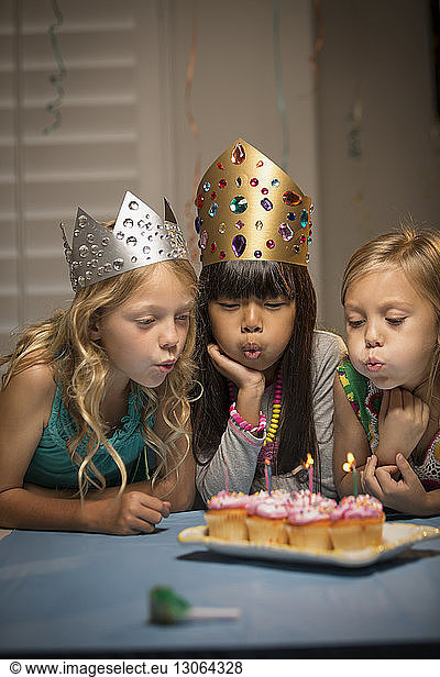 Girls blowing candles on cup cakes