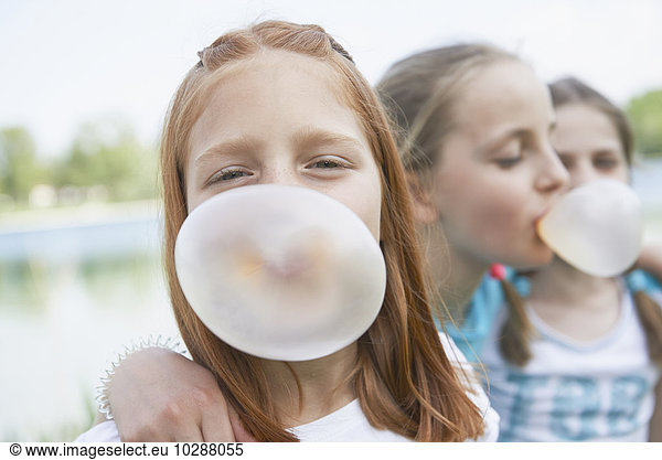 Girls blowing chewing gum bubbles  Bavaria  Germany