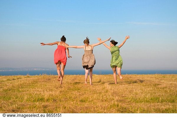 Girls dancing on grassy cliff top
