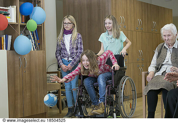 Girls playing bowling with senior woman in rest home