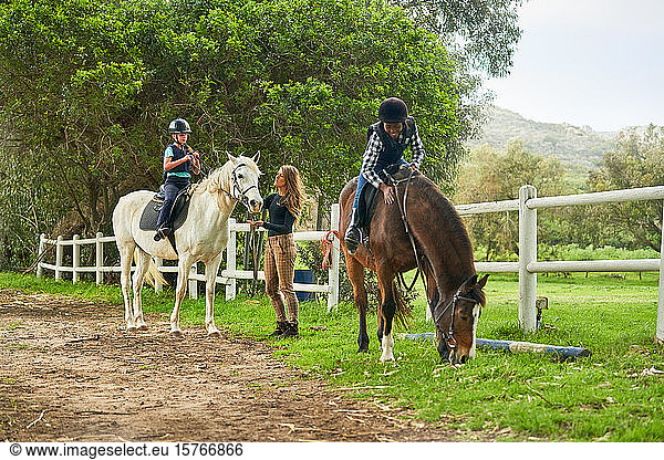 Girls preparing for horseback riding lesson at rural paddock