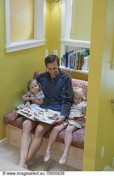Girls reading with their father in sitting room of a disability accessible home