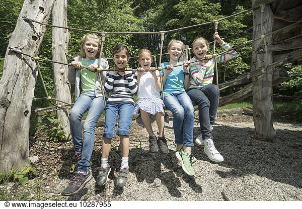 Girls sitting on rope bridge in playground  Munich  Bavaria  Germany
