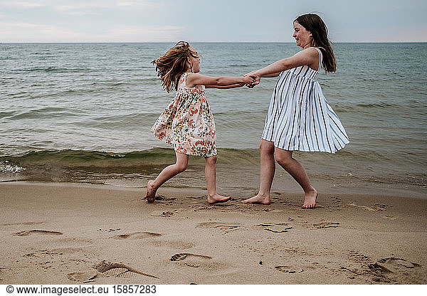 girls spinning and playing on beach along lake michigan