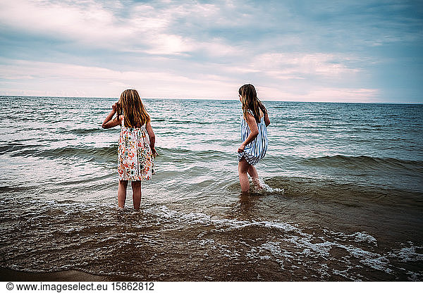 girls standing in lake in their dresses looking away from camera