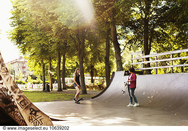 Girls standing on ramp at skateboard park