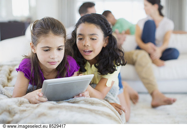 Girls using digital tablet on sofa in living room