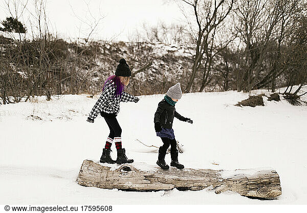 Girls walking on log in winter