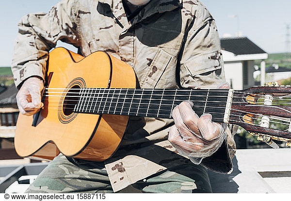 Gitarre spielender Soldat  mit Schutzhandschuhen