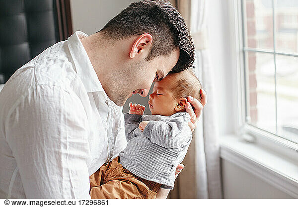 Glücklich stolzer Vater umarmt küssen neugeborenes Baby Junge. Bindung mit Kind.