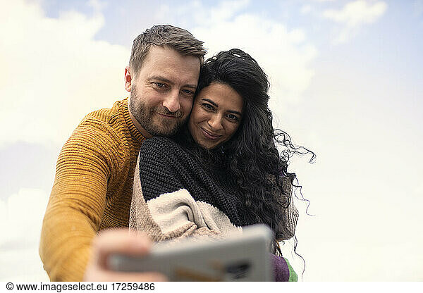 Glücklich zärtliches Paar in Pullover nehmen selfie