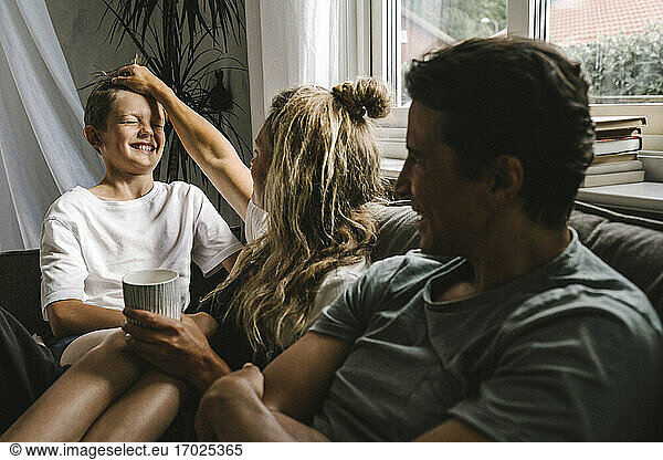 Glückliche Eltern verbringen Zeit mit Sohn im Wohnzimmer