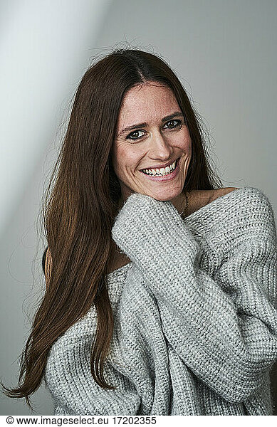 Glückliche erwachsene Frau im Pullover auf grauem Hintergrund