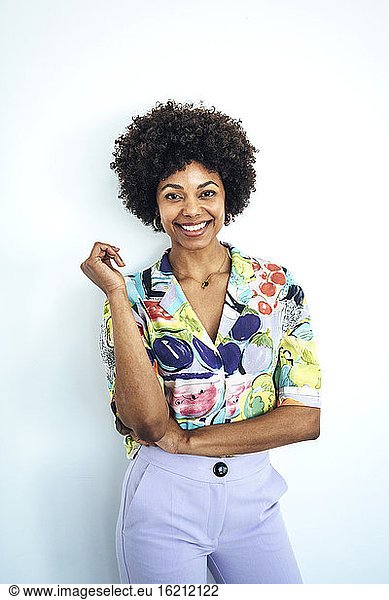 Glückliche erwachsene Frau mit Afrofrisur vor weißem Hintergrund