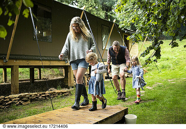 Glückliche Familie hält die Hände zu Fuß außerhalb Hütte im Wald